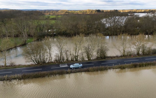 Motorists cross floodwaters from the River Beult following heavy rain near Ashford in Kent.