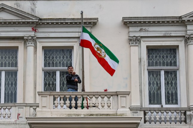 ?? Licensed to London News Pictures. 10/01/2026. London, UK. An Iranian protester replace the flag of the Islamic Republic of Iran with the pre-revolution Lion and Sun flag outside Embassy of The Islamic Republic of Iran in central London as hundreds of demonstrators call for political change and showing solidarity with anti-government protests in Iran. Photo credit: Dinendra Haria/LNP