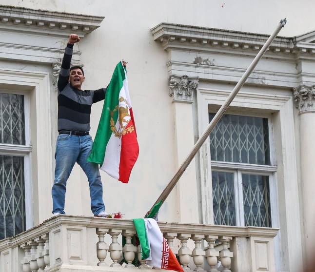 ?? Licensed to London News Pictures. 10/01/2026. London, UK. An Iranian protester replace the flag of the Islamic Republic of Iran with the pre-revolution Lion and Sun flag outside Embassy of The Islamic Republic of Iran in central London as hundreds of demonstrators call for political change and showing solidarity with anti-government protests in Iran. Photo credit: Dinendra Haria/LNP