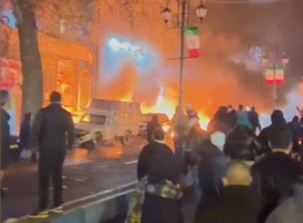 Demonstrators walk past burning cars in IRAN. Saturday 10 January 2026 Source BBC