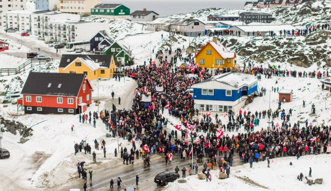 This aerial view taken by Mads Schmidt Rasmussen and handed out by Arctic Creative shows people as they take part in a demonstration that gathered almost a third of the city population to protest against the US President's plans to take Greenland, on January 17, 2026 in Nuuk, Greenland. US President Donald Trump escalated his quest to acquire Greenland, threatening multiple European nations with tariffs of up to 25 percent until his purchase of the Danish territory is achieved. Trump's threats came as thousands of people protested in the capital of Greenland against his wish to acquire the mineral-rich island at the gateway to the Arctic. (Photo by Mads Schmidt Rasmussen / various sources / AFP via Getty Images) / RESTRICTED TO EDITORIAL USE - MANDATORY CREDIT: ARCTIC CREATIVE / Mads Schmidt Rasmussen - DISTRIBUTED TO CLIENTS AS A SERVICE